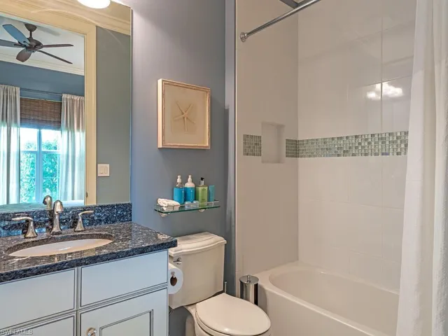 Full bathroom featuring ceiling fan, vanity, shower / tub combo, crown molding, and toilet