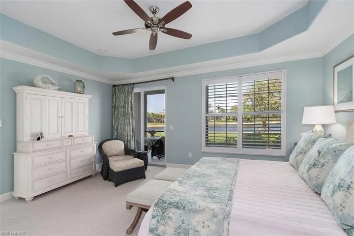 Bedroom with a raised ceiling, ceiling fan, light colored carpet, and access to exterior