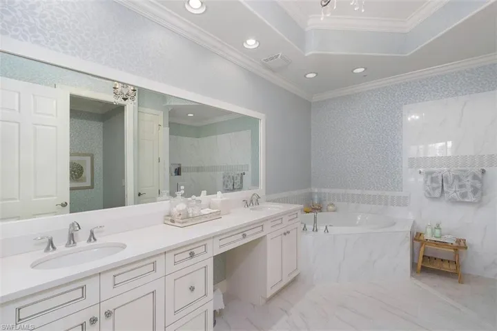 Bathroom featuring ornamental molding, vanity, and separate shower and tub