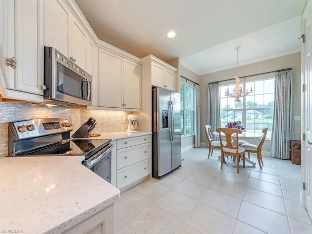 Kitchen featuring light tile patterned flooring, appliances with stainless steel finishes, a chandelier, and white cabinetry