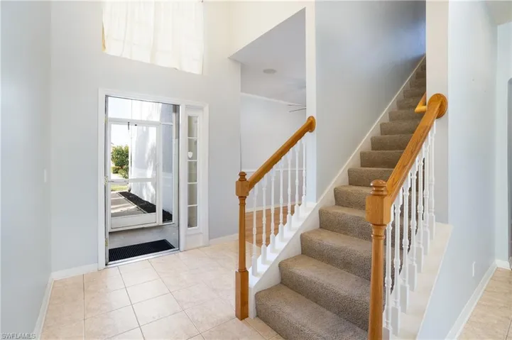 Foyer entrance with light tile patterned floors and stairs