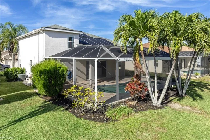 Back of property with a sunroom, a lanai, and a yard