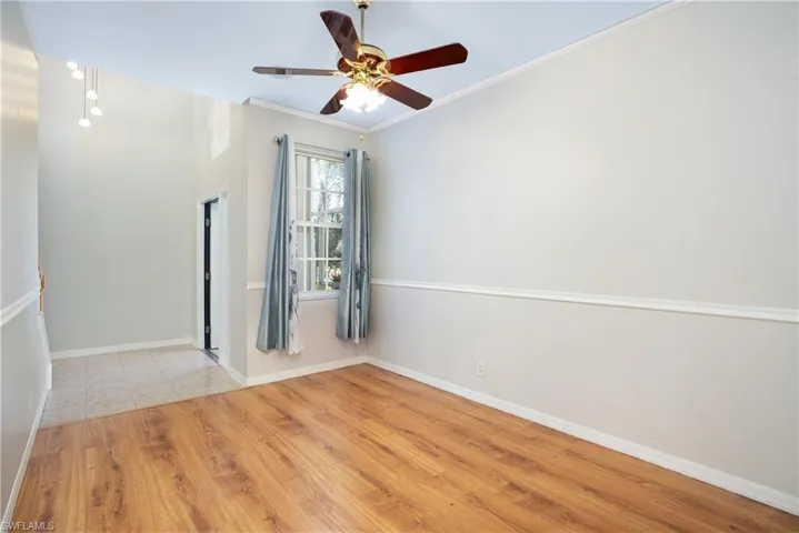 Empty room featuring light wood-type flooring, ornamental molding, and ceiling fan