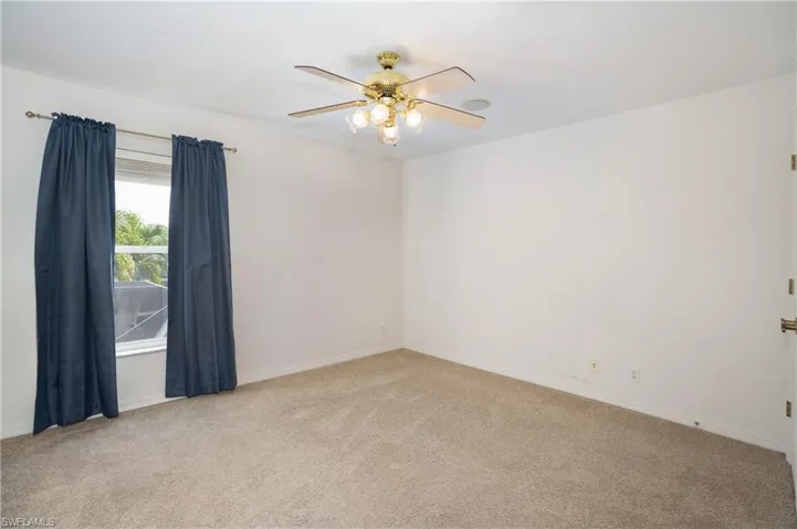 Carpeted spare room featuring baseboards and ceiling fan