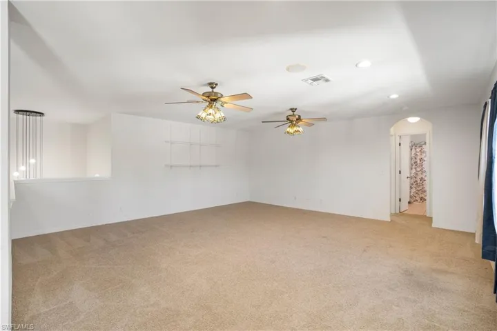 Spare room featuring arched walkways, light carpet, ceiling fan, and recessed lighting