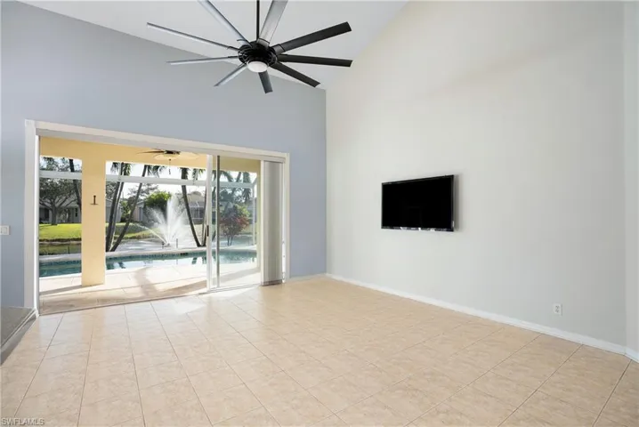 Empty room with high vaulted ceiling, a sunroom, and a ceiling fan