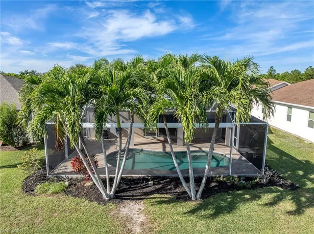 Swimming pool featuring a lawn, a sunroom, and a lanai