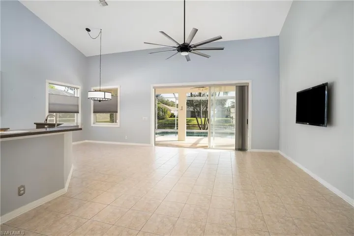 Unfurnished living room with high vaulted ceiling, healthy amount of natural light, a ceiling fan, and light tile patterned floors