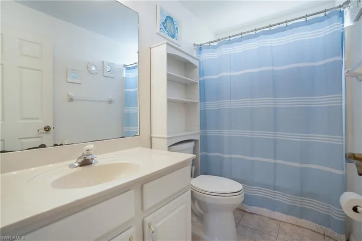 Full bath featuring light tile patterned floors, curtained shower, and vanity