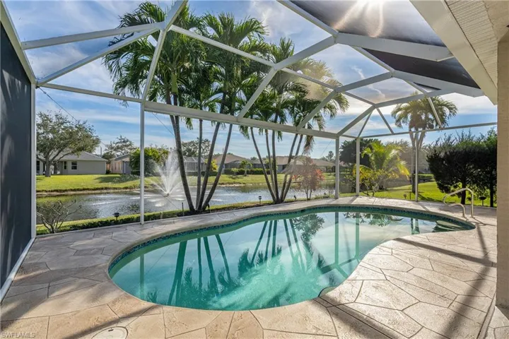 Swimming pool featuring a sunroom, a water view, glass enclosure, and a patio