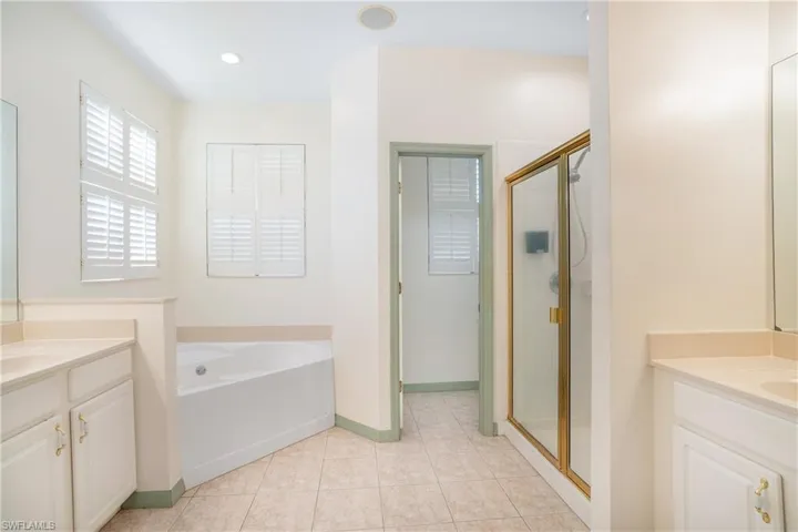 Bathroom with vanity, a garden tub, a shower stall, and light tile patterned floors