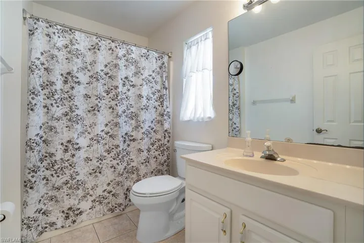 Full bathroom featuring vanity, light tile patterned floors, and curtained shower