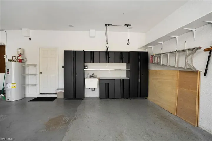 Garage featuring electric water heater and a sink