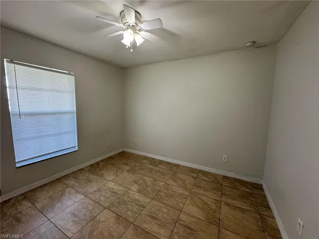 Unfurnished room featuring a ceiling fan, tile patterned flooring, and baseboards