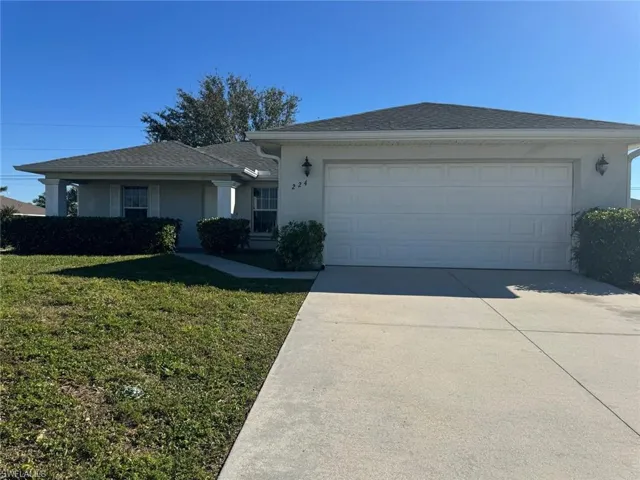 Ranch-style house with driveway, a garage, a front yard, stucco siding, and a shingled roof