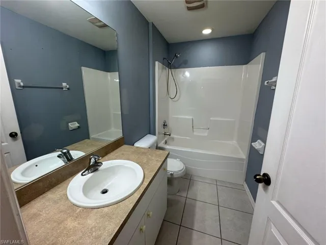 Bathroom featuring shower / bathing tub combination, tile patterned floors, toilet, and vanity