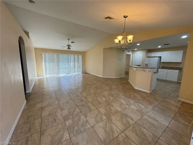 Kitchen featuring visible vents, white fridge with ice dispenser, ceiling fan with notable chandelier, open floor plan, and vaulted ceiling