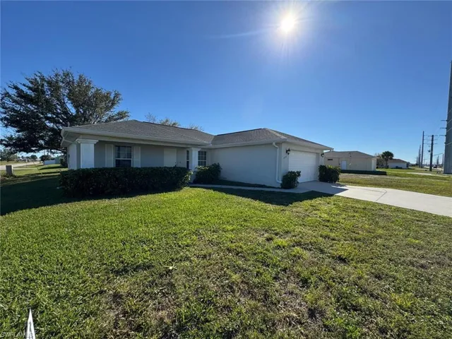 Ranch-style house featuring a front yard, concrete driveway, stucco siding, and an attached garage