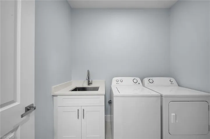 Washroom with washing machine and clothes dryer, cabinet space, and a sink