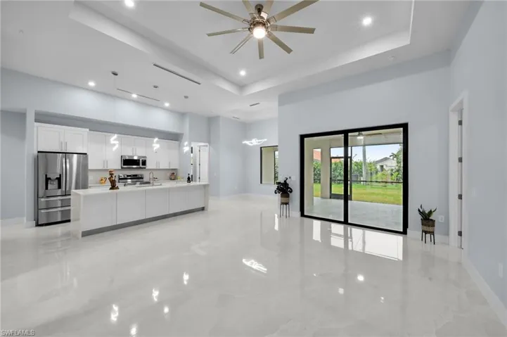 Living room featuring baseboards, a tray ceiling, recessed lighting, a towering ceiling, and marble finish floor