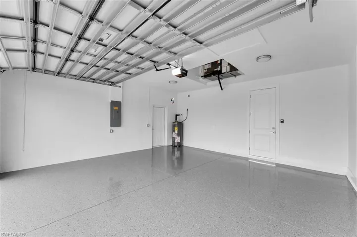 Garage with electric panel, water heater, and a garage door opener