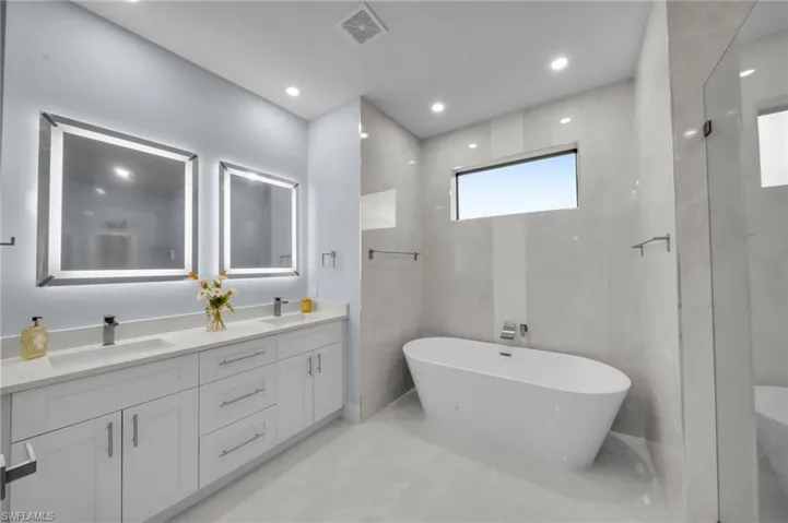 Full bath with double vanity, visible vents, marble finish floor, and a sink