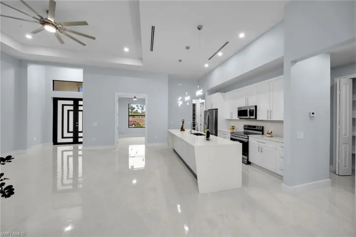 Kitchen featuring a center island with sink, light countertops, a tray ceiling, appliances with stainless steel finishes, and white cabinetry