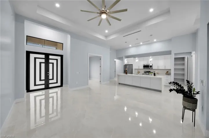 Living room with recessed lighting, baseboards, a raised ceiling, and a high ceiling