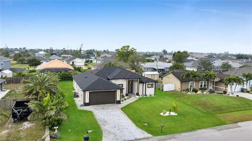 View of front facade with a garage, a residential view, a front lawn, and decorative driveway