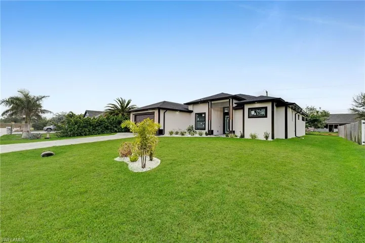 View of front of property featuring concrete driveway, a garage, and a front yard