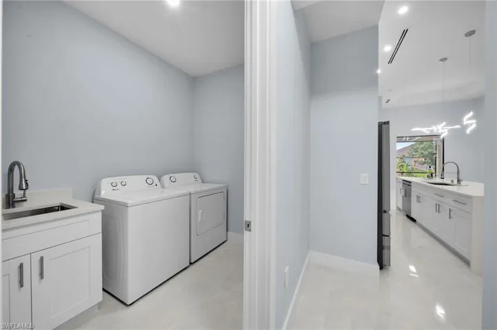 Laundry room with laundry area, washer and dryer, baseboards, and a sink