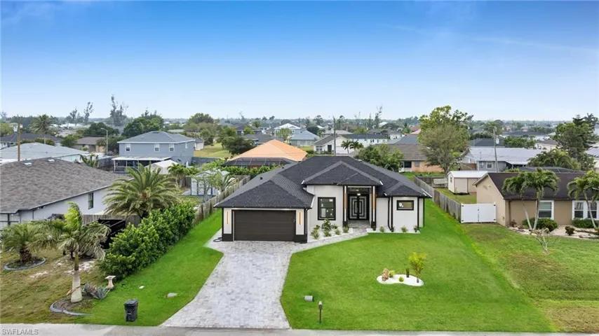 View of front of home with a front yard, fence, a garage, decorative driveway, and a residential view