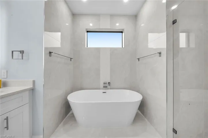 Full bathroom with a stall shower, vanity, tile walls, and a freestanding tub