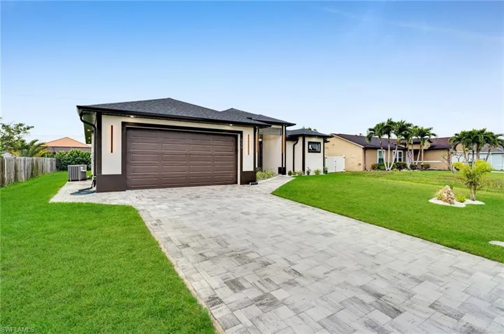 View of front of home with cooling unit, stucco siding, a front lawn, a garage, and decorative driveway