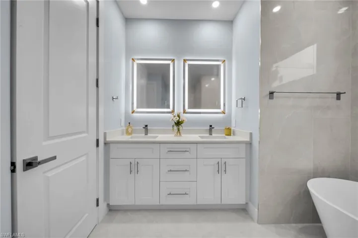 Bathroom featuring a sink, a soaking tub, recessed lighting, and double vanity