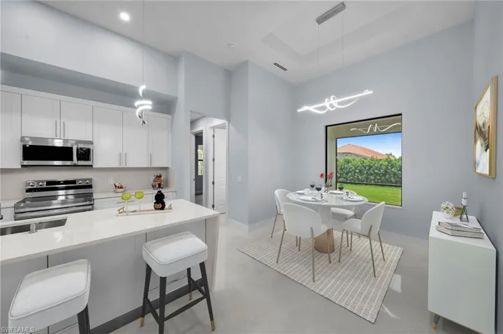 Kitchen featuring a kitchen bar, appliances with stainless steel finishes, finished concrete flooring, and white cabinetry