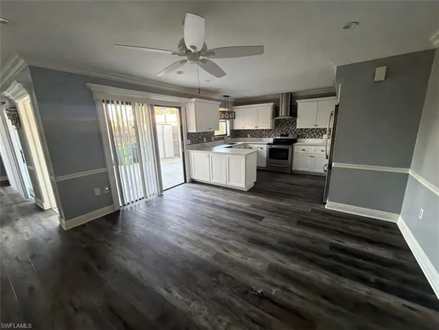 Kitchen with white cabinetry, light countertops, appliances with stainless steel finishes, backsplash, and crown molding