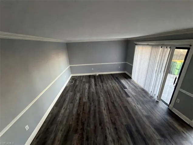 Empty room with dark wood-style floors and crown molding