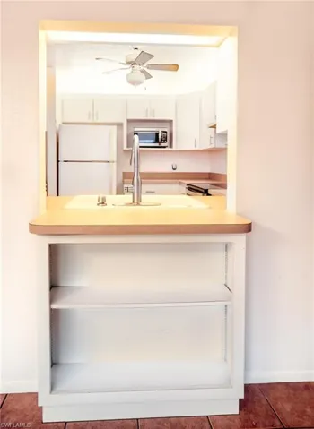 Kitchen featuring ceiling fan, sink, dark tile patterned floors, and white fridge