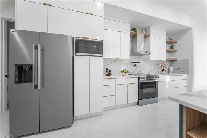 Kitchen with open shelves, appliances with stainless steel finishes, and white cabinetry