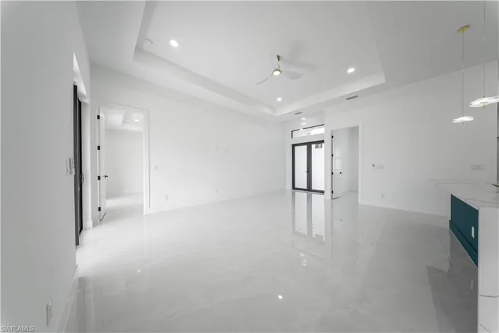 Empty room featuring a raised ceiling, ceiling fan, recessed lighting, and light marble finish floors