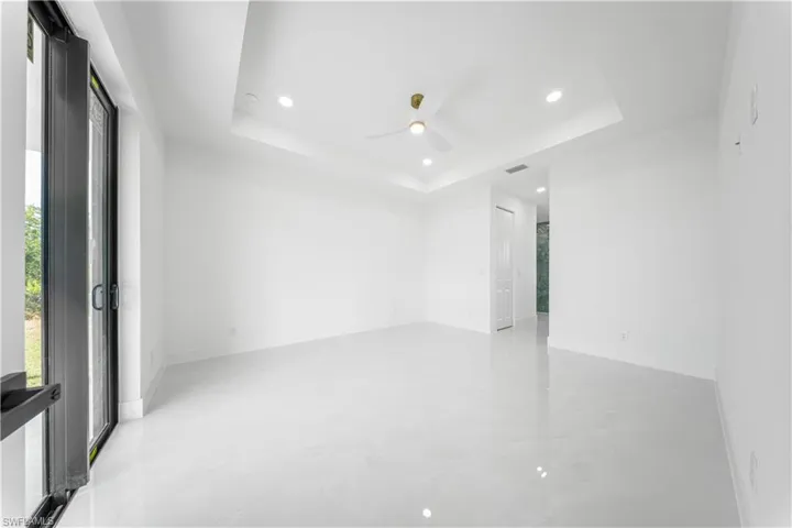 Empty room with a tray ceiling, recessed lighting, and ceiling fan