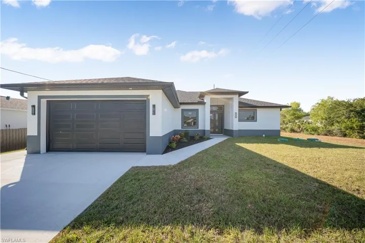 Prairie-style home with stucco siding, a front yard, driveway, a garage, and a shingled roof