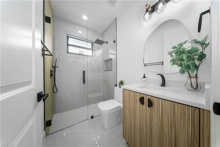 Full bath featuring vanity, a marble finish shower, light marble finish flooring, and recessed lighting