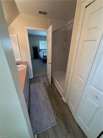 Ensuite bathroom featuring a shower stall, vanity, and dark wood-type flooring