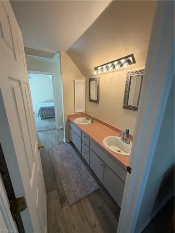 Bathroom featuring double vanity, dark wood finished floors, and ensuite bathroom