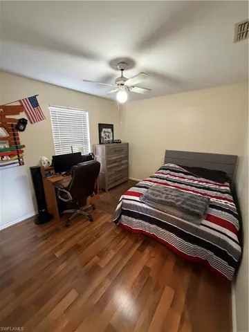 Bedroom featuring an office area, dark wood finished floors, and ceiling fan