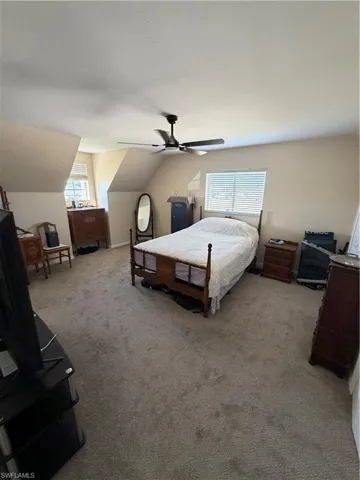 Bedroom featuring vaulted ceiling, light colored carpet, and a ceiling fan
