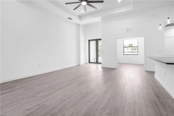 Unfurnished living room with a towering ceiling, light wood finished floors, ceiling fan, and recessed lighting