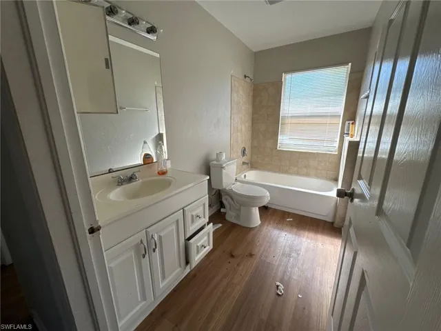 Full bathroom with vanity,  shower combination, toilet, and wood-type flooring